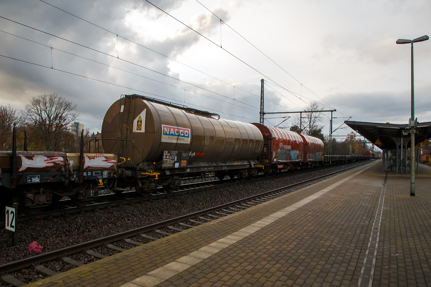 Vierachsiger 75 m³ Drehgestell-Kesselwagen, 37 80 7931 640-2 D-VTGCH, der Gattung Zacens, der VTG Rail Europe GmbH (ein ehem. NACCO Waggon) am 07.12.2022 im Zugverband bei einer Zugdurchfahrt im Bahnhof Dresden-Strehlen. Im Jahr 2018 hat die VTG sämtliche Anteile der CIT Rail Holdings (Europe) SAS übernommen, zu der auch die die NACCO-Gruppe mit 11.000 Güterwagen gehörte. 

Das Ladegut ist hier Natriumcyanid Lösung, was auch die Gefahrguttafel (66/2031) zeigt: (oben) Gefahrgutnummer 66 = sehr giftiger Stoff / (unten) UN-Nummer 3414 = Natriumcyanid Lösung. Natriumcyanid ist das Natriumsalz der Blausäure (HCN). Bei Raumtemperatur ist es ein farbloses, hygroskopisches kristallines Pulver, das leicht bittermandelartig riecht. In Gegenwart von Säuren zersetzt es sich in das hochtoxische Gas Blausäure (Cyanwasserstoff). 

Verwendung:
Natriumcyanid wird zusammen mit Kaliumcyanid zur Gewinnung von Gold, Silber und anderen Metallen verwendet. In der Galvanotechnik wird es für verschiedene cyanidische Bäder genutzt. Bei der Metallbearbeitung kommt geschmolzenes Natriumcyanid zum Härten bestimmter Stahlsorten (Einsatzstähle) zum Einsatz.

Die Bedeutung der Gattungs- und Kennbuchstaben (hier Zacens):
Z - Kesselwagen für den Transport von flüssigen oder gasförmigen Erzeugnissen
a - mit vier Radsätzen
c - mit Entladung unter Druck
e - mit Heizeinrichtung
n - mit vier Radsätzen höchste Lastgrenze über 60 t
s - Höchstgeschwindigkeit 100 km/h (beladen)