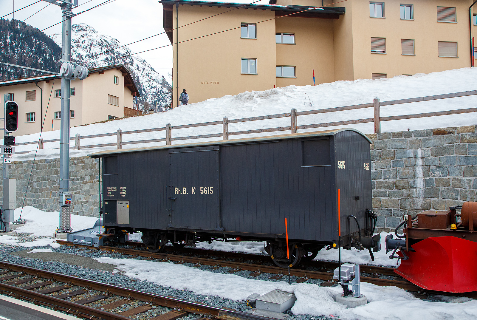 Zweiachsiger gedeckter G�terwagen RhB K1 5615 �Il Grischun� (Baujahr 1913) vom Club 1889 (2003 bis 2004) aufgearbeitet, abgestellt am 21.03.2023 im Bahnhof Pontresina.Ein typischer, fr�her weitverbreiteter, gedeckter RhB-G�terwagen aus einer Serie von ehemals 115 St�ck, im Volksmund als „Viehwagen“ bekannt, als letzter Vertreter daher seltener historischer G�terwagen.

Der Wagen wurde 1913 von De Dietrich & Cie. in Bad Niederbronn (Elsass) gebaut. 

Mit dem weiteren Ausbau des Streckennetzes stieg auch der Bedarf an neuen Fahrzeugen f�r den G�tertransport. Zwischen 1911 und 1913 beschaffte die RhB unteranderem 115 gedeckte G�terwagen der Gattung K1 mit Holzbeplankung. 1949/50 r�stete man zahlreiche Fahrzeuge auf Stahlaufbauten um, ab Mitte der 70er Jahre erfolgte eine zweite Modernisierungsphase, nach der nur noch wenige Fahrzeuge mit Holzkastenaufbau im Dienst verblieben. 2004 nahm der Club 1889 den Gbk-v 5615 als RhB-Nostalgieg�terwagen wieder in Betrieb.

Fr�here und aktuelle Bezeichnung:
•	1913 als Rh.B. K1 5615
•	1969 als RhB Gbk-v 5615
•	1970 als RhB Xk-v 9077 (Bahndienst)
•	1996 als RhB Xk-v 9398 (Bahndienst)
•	2004 als RhB K1 5615 (WN 9852)

TECHNISCHE DATEN: Steckbrief
Besteller: RhB
Inbetriebsetzungsjahr: 1913
Baufirma: De Dietrich & Cie. Niederbronn
Spurweite: 1.000 mm (Meterspur)
Anzahl Achsen: 2
L�nge �ber Puffer: 8.450 mm
Achsstand: 4.200 mm
Leergewicht: 6.650 kg
Ladegewichtgewicht: 12 500 kg (Tragf�higkeit 13.125 kg)
Ladefl�che: 31,88 m�
Maximalgeschwindigkeit: 60 km/h (Reihe R)
Heizung: Stammnetz, Dampfdurchleitung
Fahrf�hig: Auf allen Strecken der RhB

Aufwand vom Club 1889 / Wert des Wagens:
Zeitaufwand: 435 Std.
Kosten f�r Material: CHF 9 500.–
Wert des Wagens: CHF 31 250.– (50.–/Std.)

